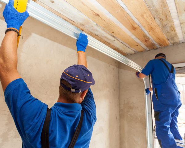 Garage doors installation. Workers installing  Post Rail and Spring Installation / Assembly.